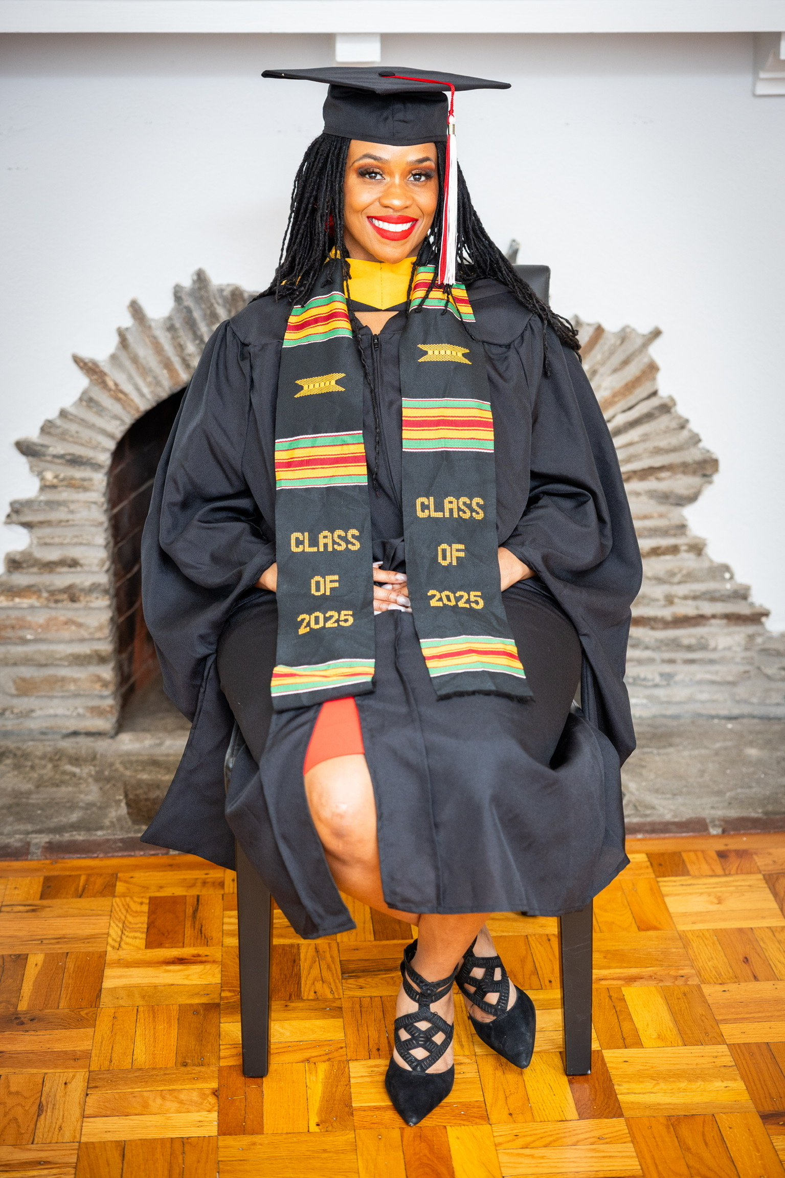 Akilah seated in her graduation cap and gown