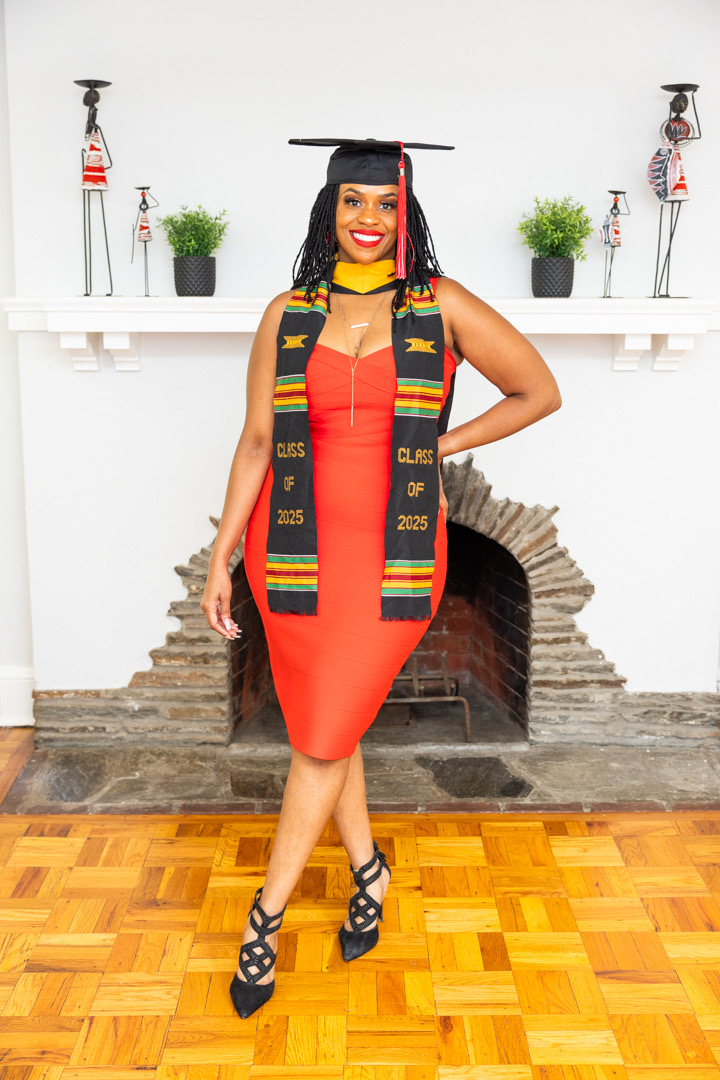Akilah celebrating graduation in a red dress, cap and stole