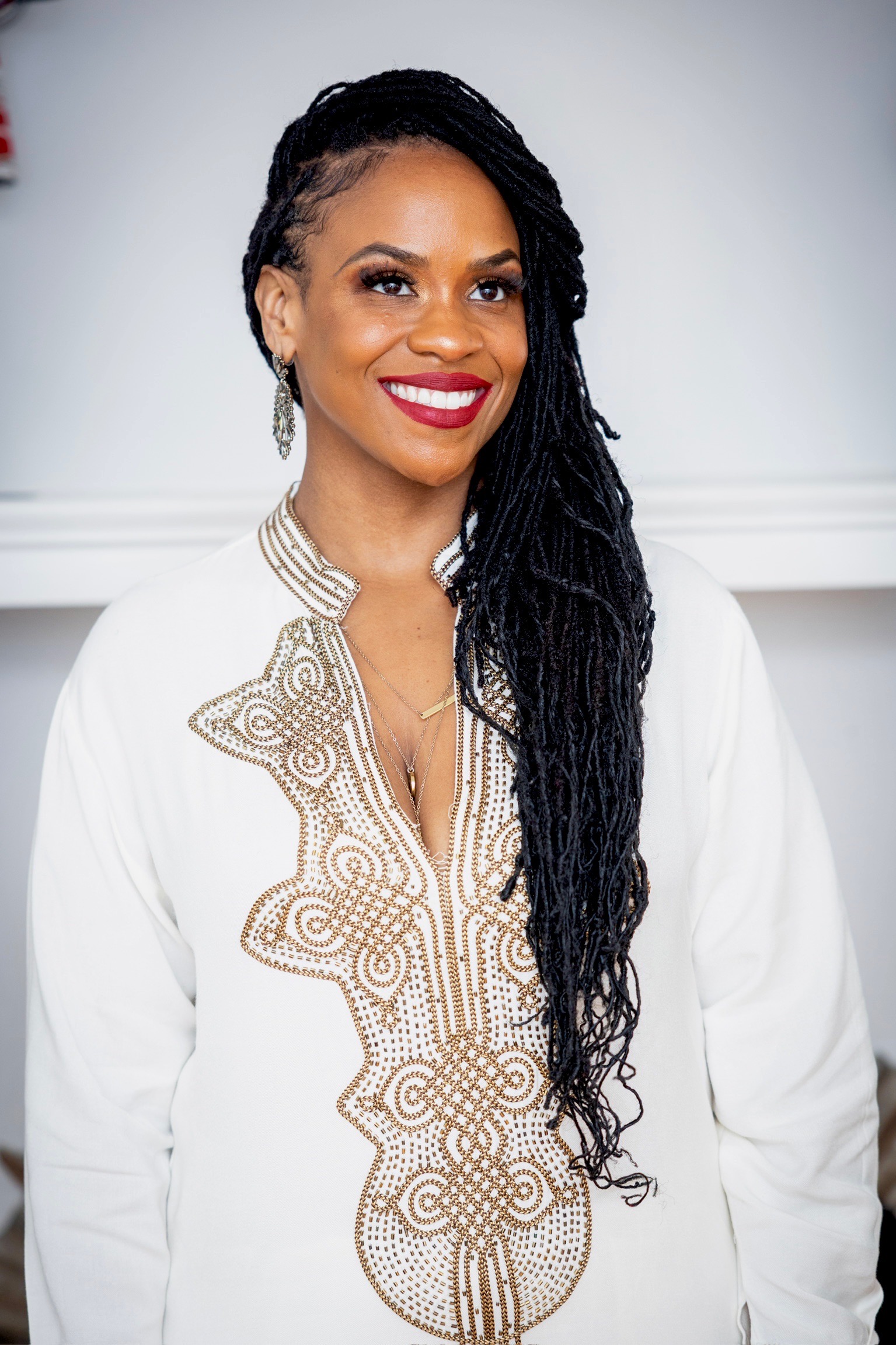 Akilah smiling in a white top with gold embroidery